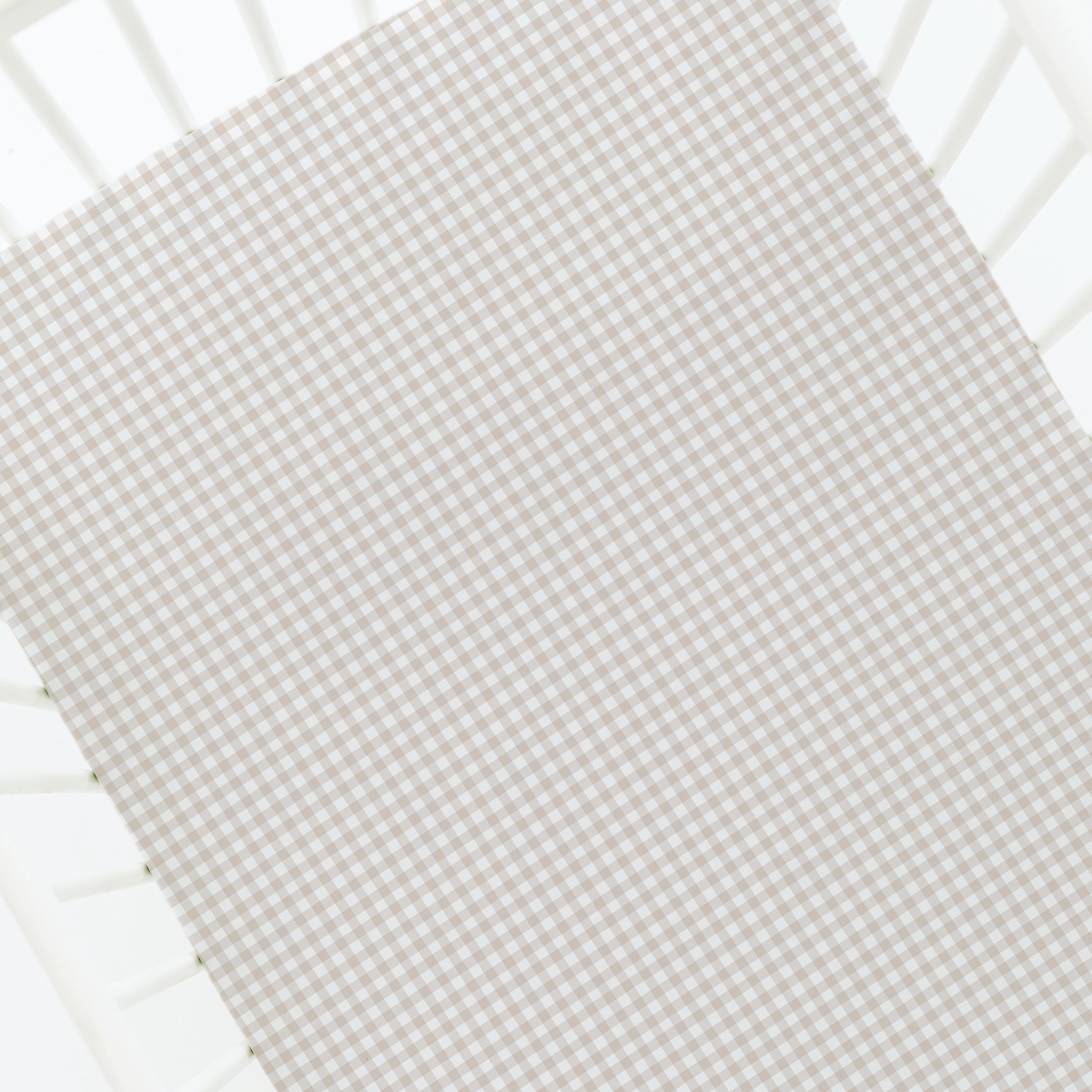 A close-up of a baby crib sheet with a light beige and white gingham checkered pattern, shown fitted inside a white crib.